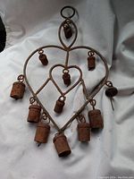 Front view showing entire heart-shaped frame with eleven small rusty hanging bells, one missing bell visible by gap.