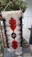 Full view of the vintage southwestern style hooked wall hanging with red, black, and cream colors, showing the full length and hanging mechanism.