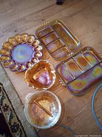 Top view of all carnival glass pieces on wooden floor showing all items in lot