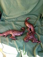 Full view of the gilt pheasant and peacock sculptures displayed together on green fabric background.