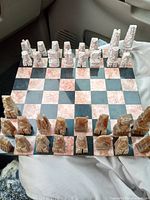 View of full chess set in board position, showing all carved pieces and marble board