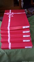 Five stacked red boxes with a printed pink ribbon design, each labeled.