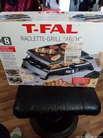 Box of T-fal Raclette Grill showing model name and usage graphics.
