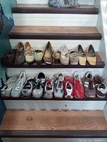 Photo showing 10 pairs of shoes arranged on stairs, 5 pairs running shoes on bottom step, 5 pairs dress shoes on upper step
