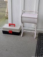 Photo of two sewing boxes: one white wooden box on stand, and one black and white plastic box with red handle and latch.