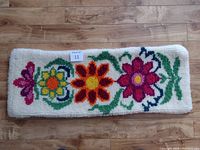 Top-down view of the rectangular hooked rug showing the colorful floral design on white background, with ruler for scale.