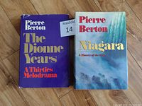 Photo of two hardcover books by Pierre Berton, 'The Dionne Years' and 'Niagara,' placed side by side on a wooden floor.