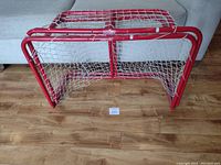 Two small red metal frame hockey nets with white netting, viewed from front
