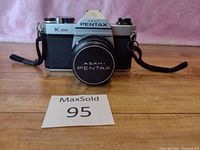 Front view of Pentax K1000 camera showing lens cap, strap, and overall body condition.