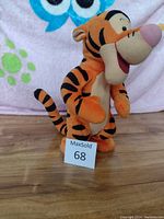 Front side view of orange and black striped Tigger plush, showing facial features and standing pose.