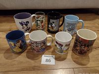 Front view of the 8 cartoon-themed mugs placed in two rows on a wooden surface.