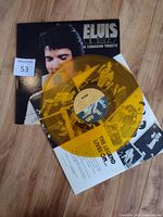 Photo showing the Elvis tribute vinyl LP with its black and white cover and yellow translucent vinyl disc laid on top.
