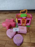 Polly Pocket playsets displayed closed, showing colorful exteriors including star, heart, flower shapes and a small house with handle.