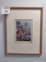Full view of framed print showing wooden frame, cream mat, and the artwork of wildflowers with subtle landscape background.