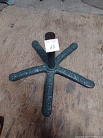 Top view of the vintage cast iron patio umbrella stand showing five decorative curved legs with floral pattern and central tube for pole insertion