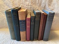 Photo showing the spines of 9 antique/vintage books standing side by side, titles including Oliver Twist and The Zeppelin's Passenger.