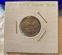 Photo of the coin housed in a white cardboard holder with handwriting indicating '1921 KGV Silver Dime'.