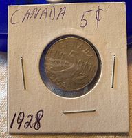 Top view of Canadian 1928 five-cent nickel coin in protective holder with handwritten notes.