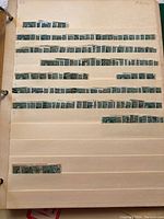 Photo of off-white album page with multiple rows of used blue George V Admiral Canadian stamps, some heavily canceled.