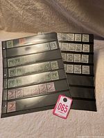 Photo showing black album page with assorted Newfoundland stamps including black and white designs in rows