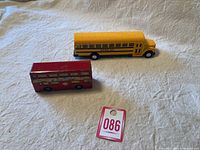 Red London double-decker bus and yellow school bus side by side on beige fabric