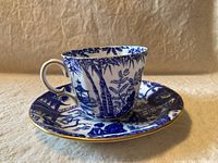 Blue and white demitasse cup with intricate Mikado pattern showing bamboo and Asian landscape details