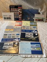 Top-down photo showing multiple Canada Post stamp presentation packs and narrative booklets arranged for display, including themes such as locomotives and wildlife.