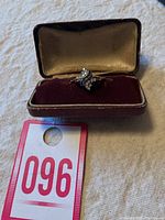 Vintage costume ring inside a velvet box with cream interior and burgundy base, shown with lot tag 096.