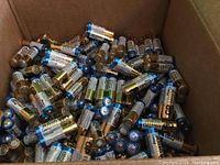 Photo of various loose AA batteries in a cardboard box showing gold and blue labeled GP Ultra Plus batteries