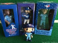 Front view of all three Toronto Blue Jays bobbleheads in original boxes with one vinyl figure in front.