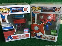 Photo showing the front of the boxed Roboto (#81) and Mantennna (#67) vinyl figures from Masters of the Universe by Funko Pop.