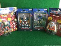 Four Masters of the Universe action figures in packaging, including Buzz Saw Hordak, Roboto, Evil Lyn, and Ram Man.
