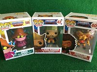 Three Funko Pop figures in original boxes from Masters of the Universe series: Orko, King Randor, Grizzlor on green background.