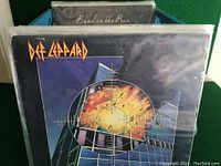 Photo showing Def Leppard vinyl LP album cover in protective plastic sleeve in crate.