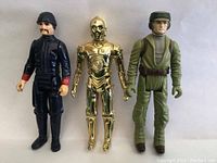 Three vintage Star Wars figures: black-clad Imperial Officer, gold C-3PO droid, green-clad Rebel Soldier