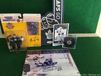 Photo showing an autographed hockey photo, 1995 Starting Lineup hockey figure, hockey puck, fan finger, and postcard.