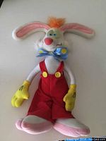 Full view of vintage Roger Rabbit plush showing red overalls, yellow gloves, large pink and white feet, light blue eyes, and orange hair tuft.