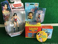 Overview of all items in the Wonder Woman collectible lot: action figure in packaging, sticker, boxed mug, boxed enamel pin.