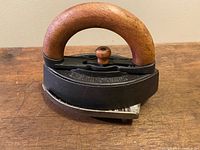 Photo showing the full smoothing iron with a wooden handle and cast iron base on a wooden surface.