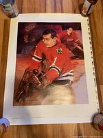 Full view of the Glenn Hall poster showing the artwork and colors on a wooden surface, held down by weights.