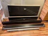 Image showing disassembled brown wood bed panels and metal frame parts laid on floor.