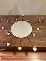 Top view of the IKEA FIGGJO 12 spoked mirror showing the large central mirror with 12 spokes each tipped with small round mirrors, placed on wooden surface.