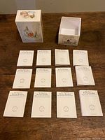 Set of 12 miniature Beatrix Potter books laid out next to an open box on a wooden surface.