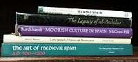 Stack of six books on Muslim and early Christian Spain including titles on Islamic Spain, al-Andalus legacy, Moorish culture, manuscript illumination, and medieval Spanish art.