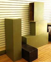Five solid wood display stands including four olive green and one brown, shown stacked and grouped