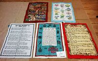 Five different tea towels laid out flat, showing various printed designs including animals, flowers, and text-based art.