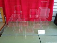 Front angle view showing 26 clear acrylic risers arranged on table against red backdrop.