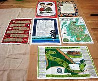 Photo showing the six tea towels laid flat on floor showing their Scottish themes including maps, poems, and traditional illustrations.