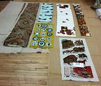 Fabric lot including several folded and rolled fabrics and panels displayed on floor showing varied prints and patterns in multiple colors.