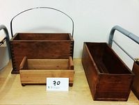 Three wooden boxes displayed on a table: one large with handle, one medium with brass corners, one small plain box.